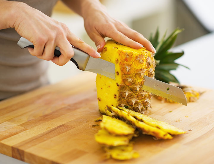 woman cutting a pineapple