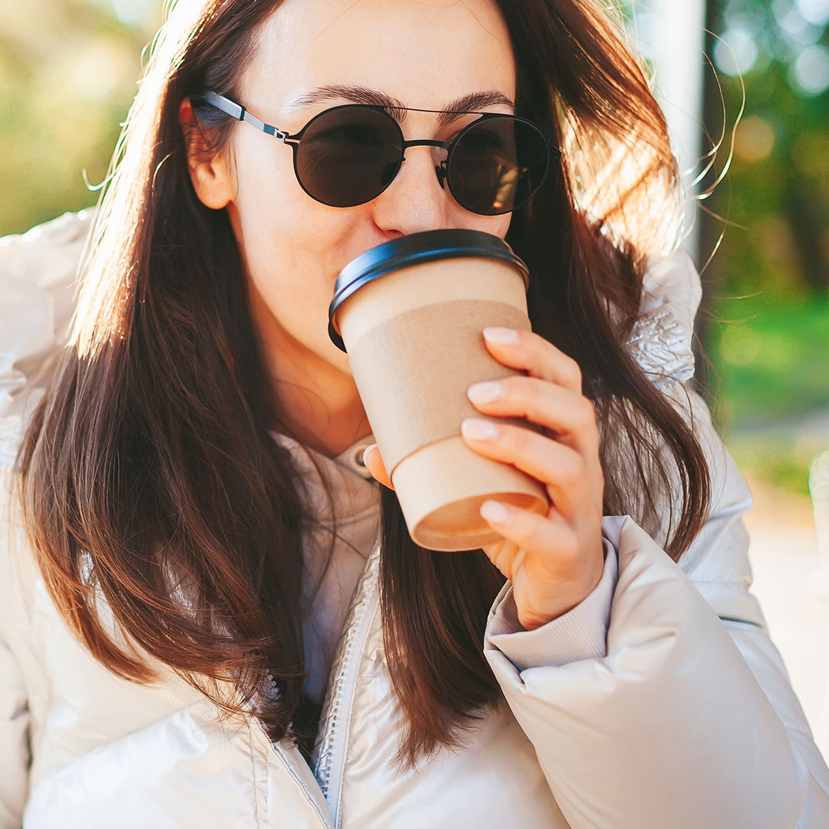 woman drinking coffee out of to-go cup