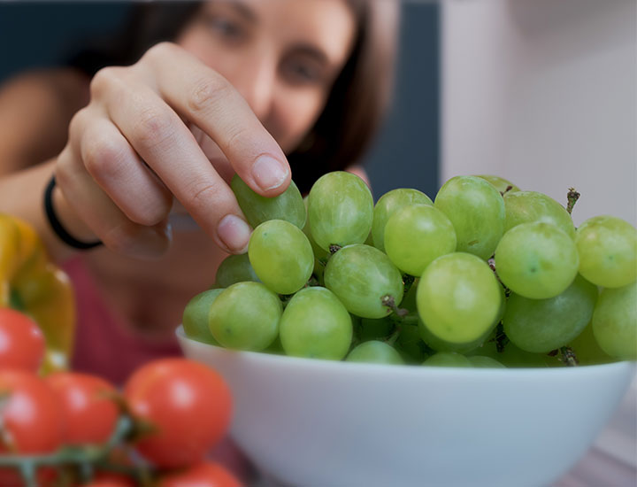 woman eating grapes from the fridge