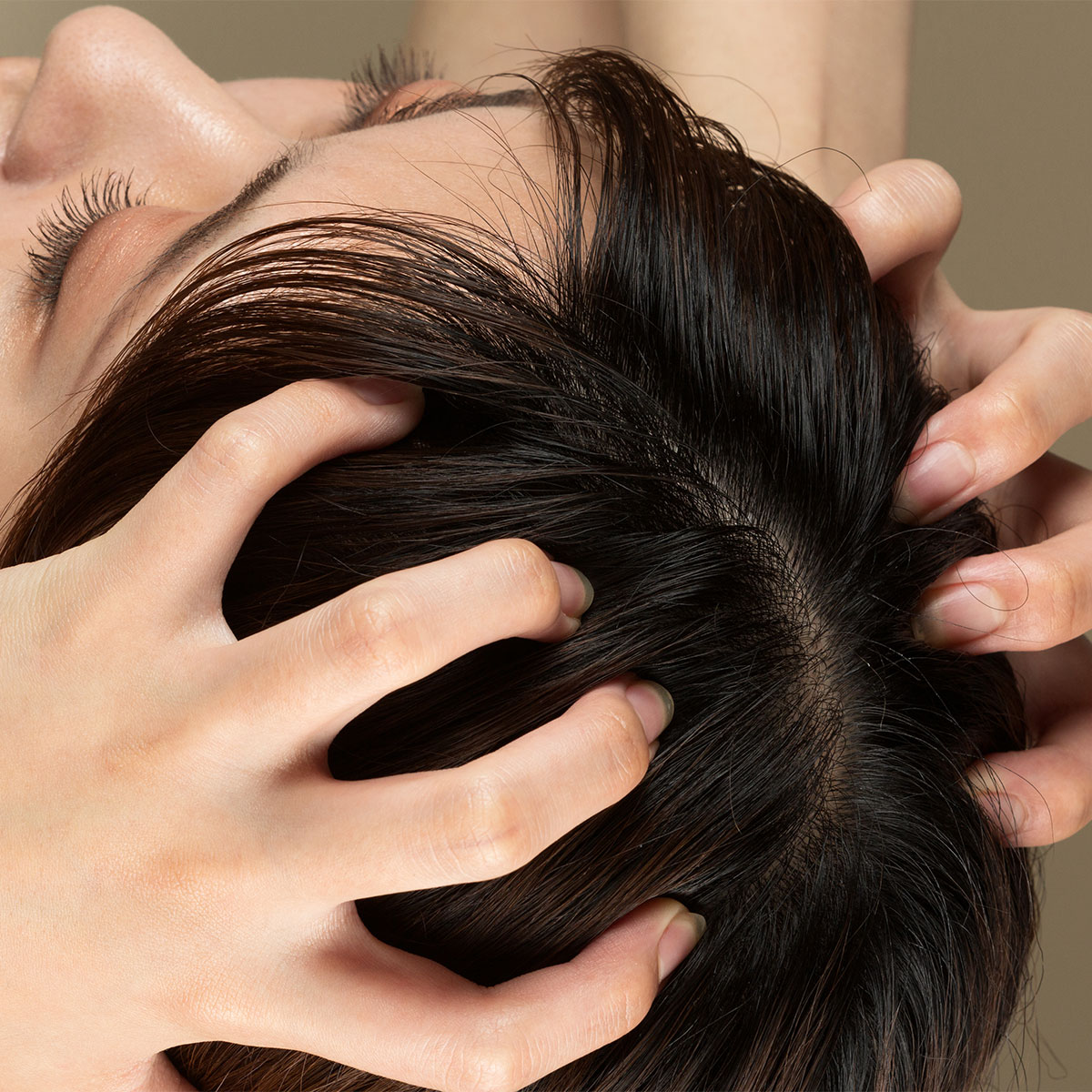 woman massaging scalp with her fingers daark hair nails