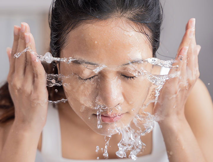 woman-splashing-face-water