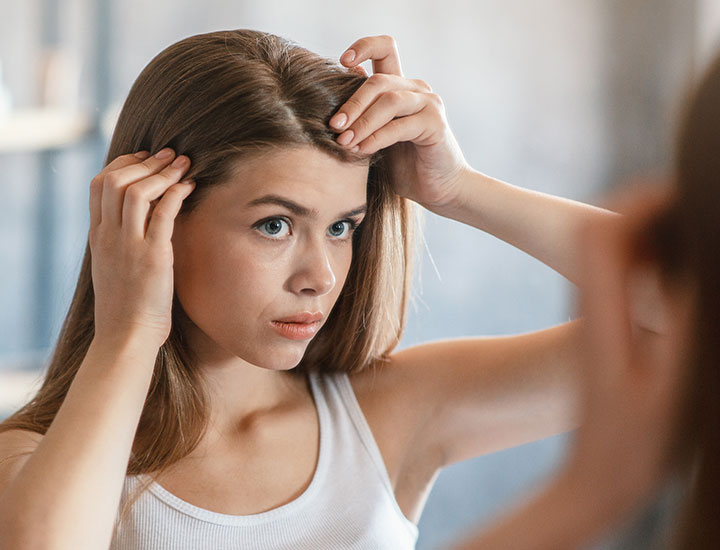 woman noticing gray hair in the mirror scalp