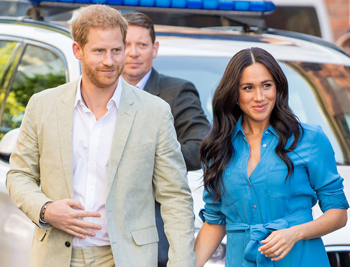 Prince Harry and Meghan Markle wearing a light suit and blue chambray dress