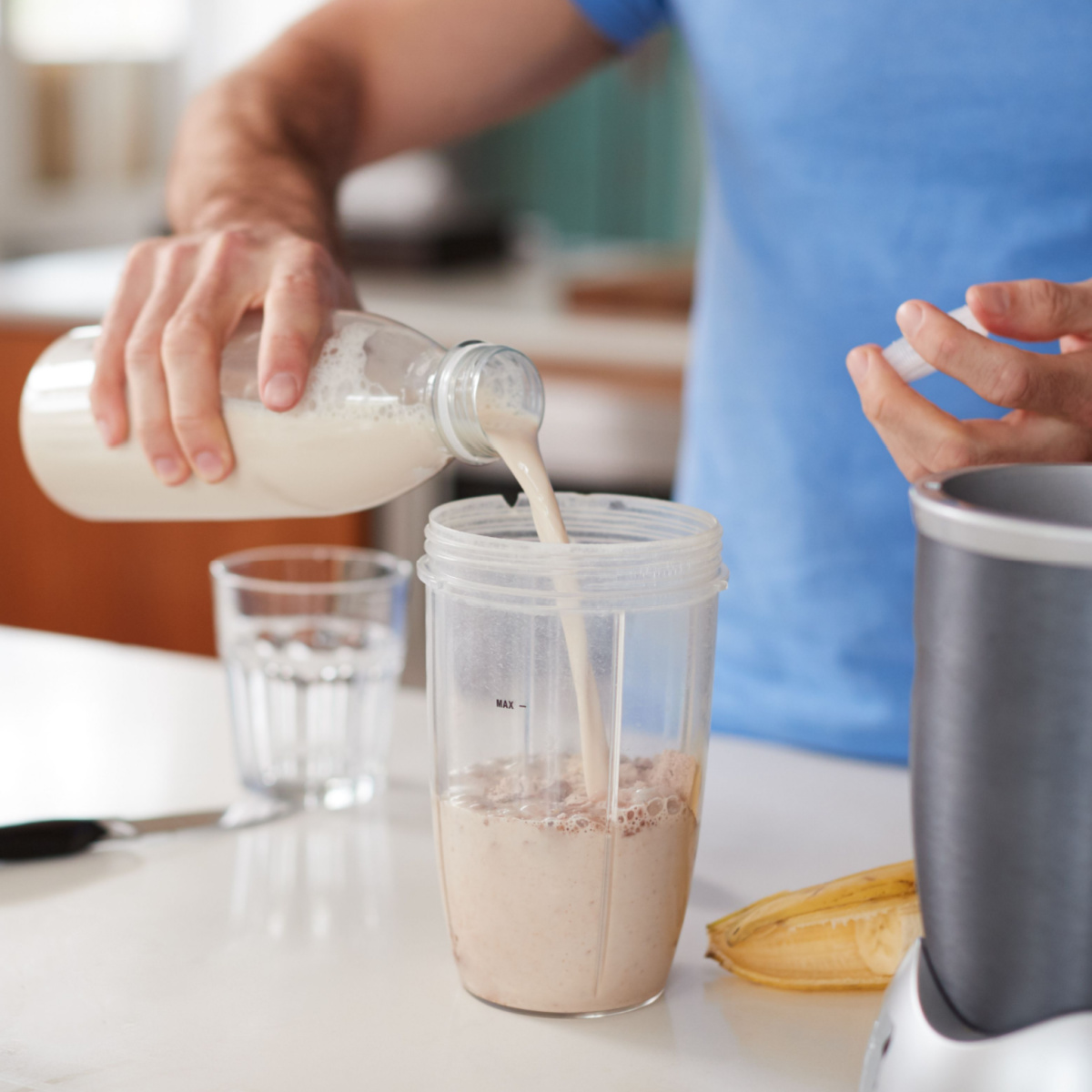 man pouring smoothie in cup