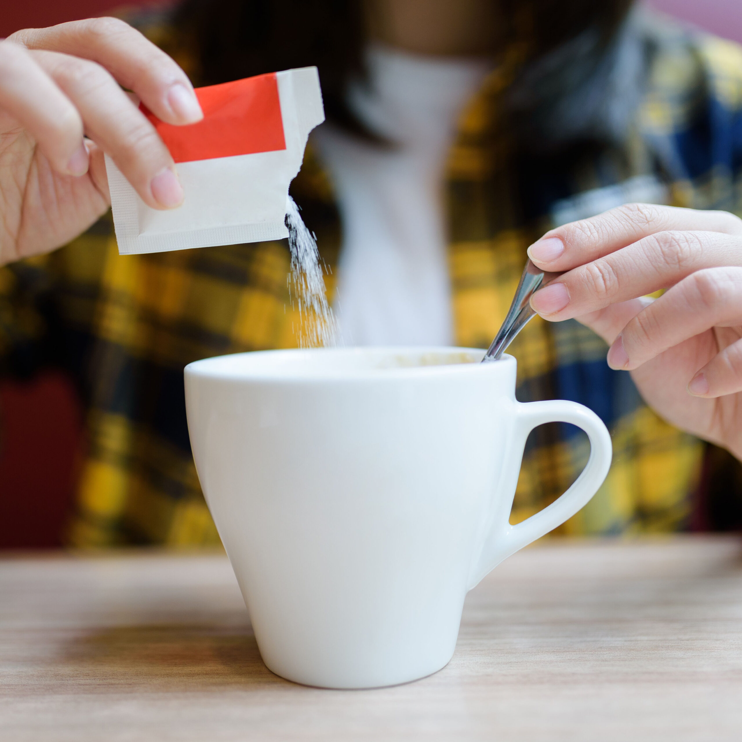 pouring artificial sweetener into coffee