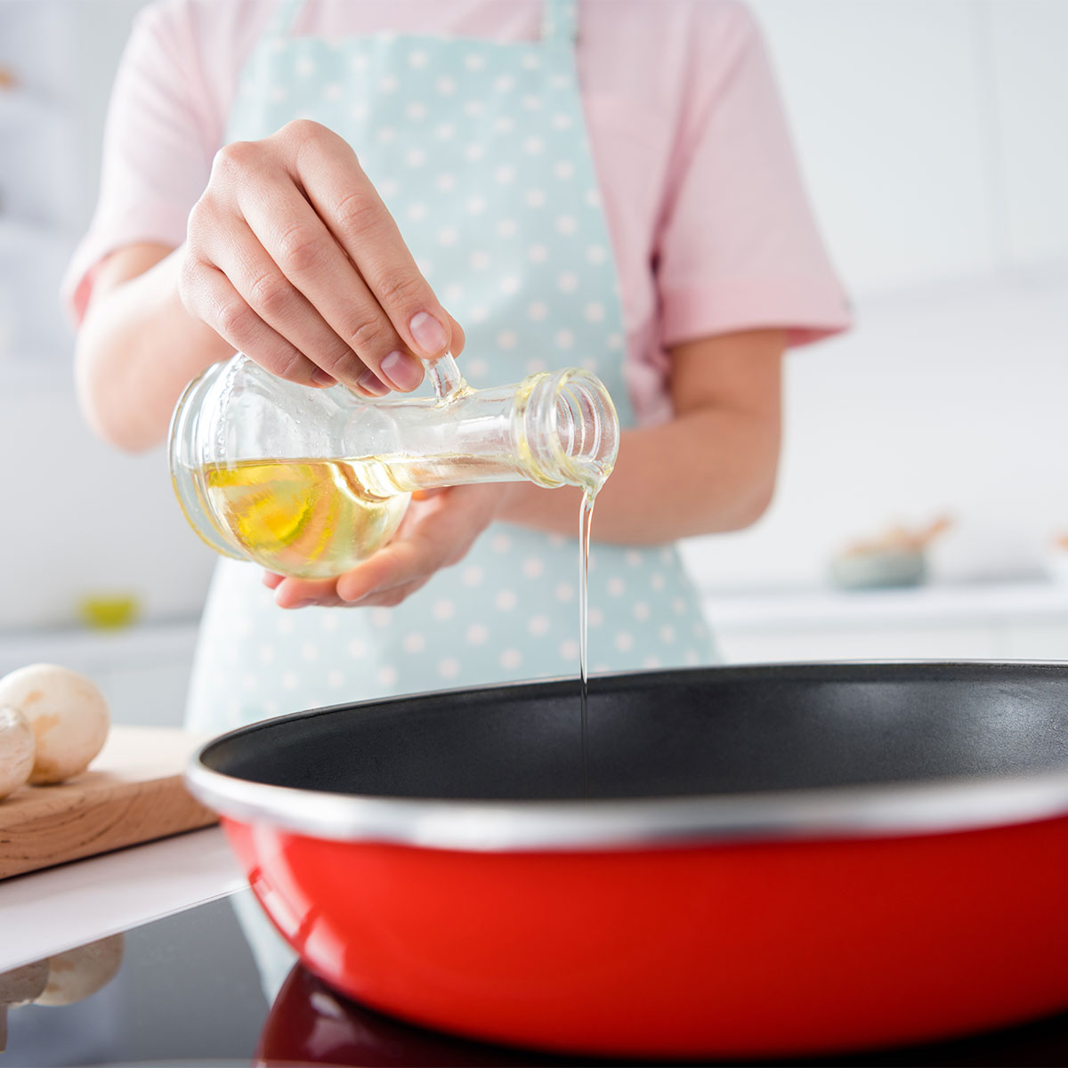 woman adding olive oil to pan