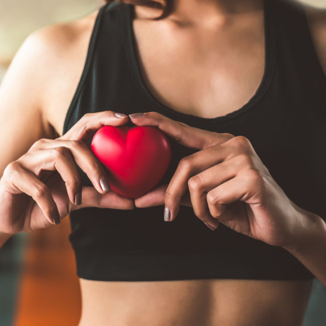 woman holding figurine in front of heart