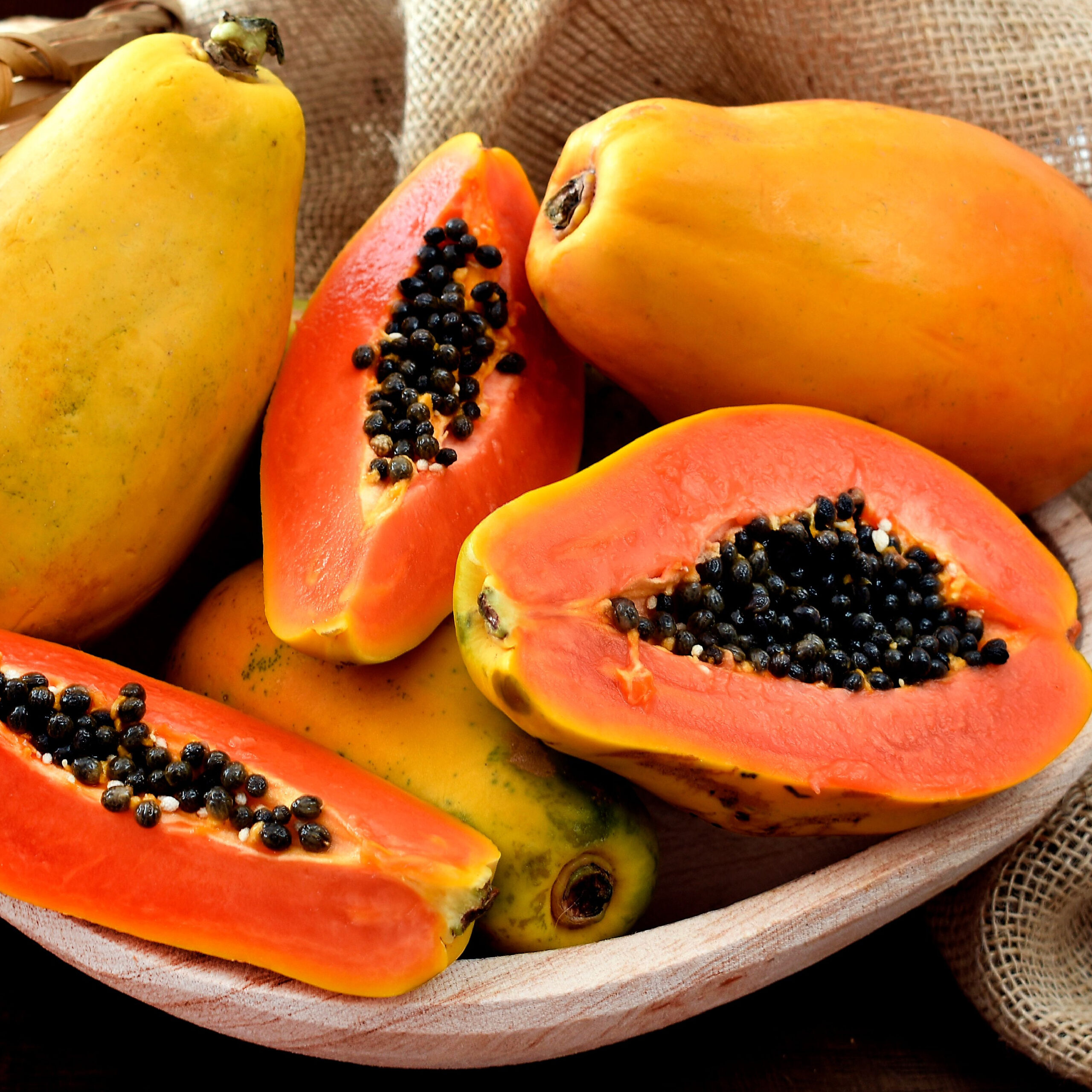 whole papayas and halved papayas in bowl