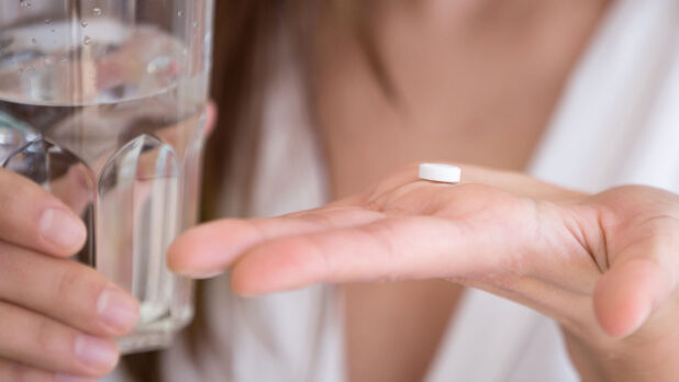 woman taking pill with glass of water