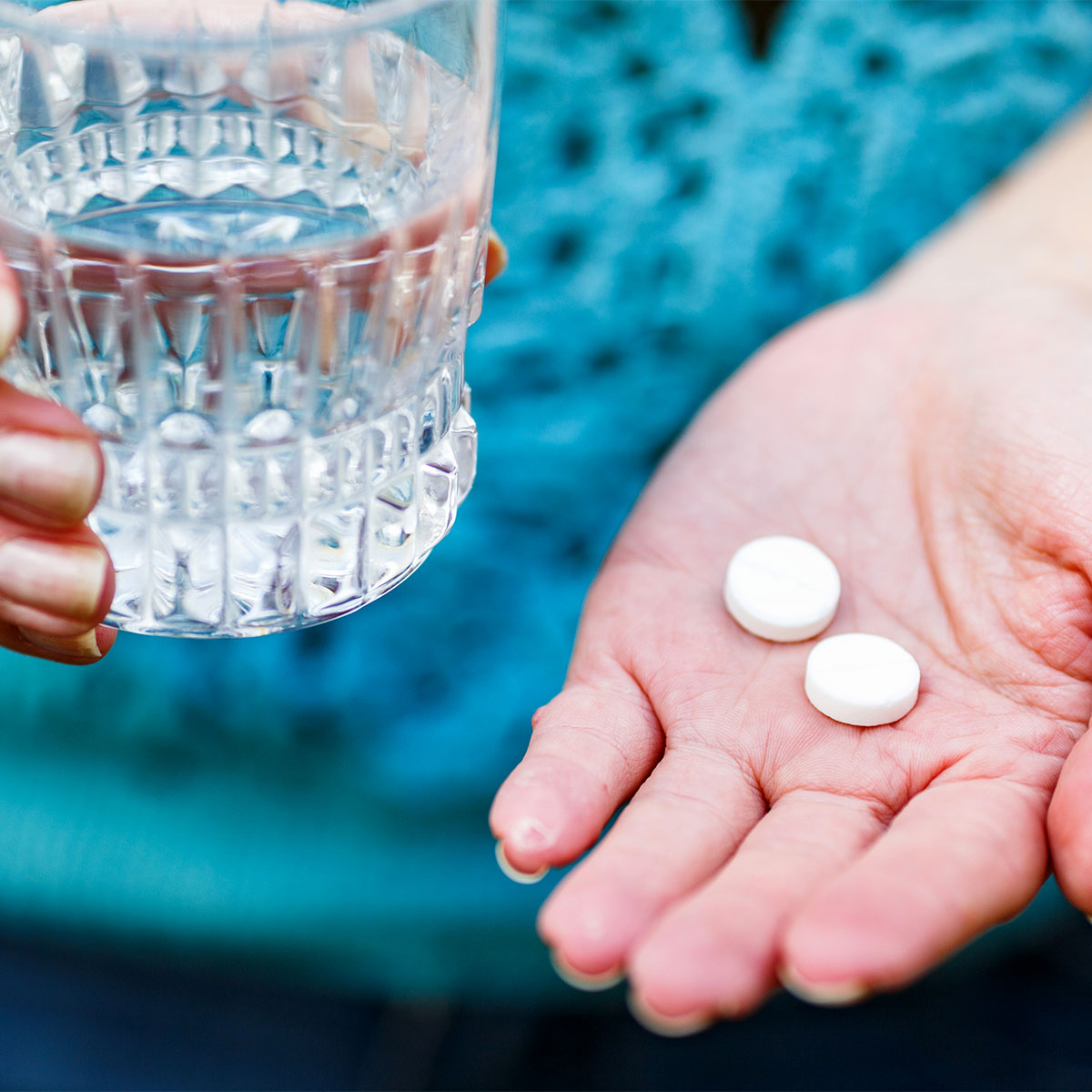 woman taking supplements with glass of water