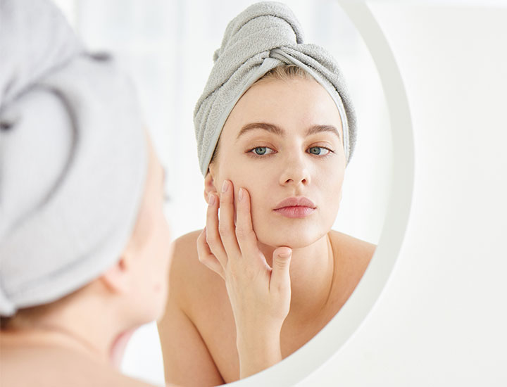 Young woman looking at her skin in a mirror