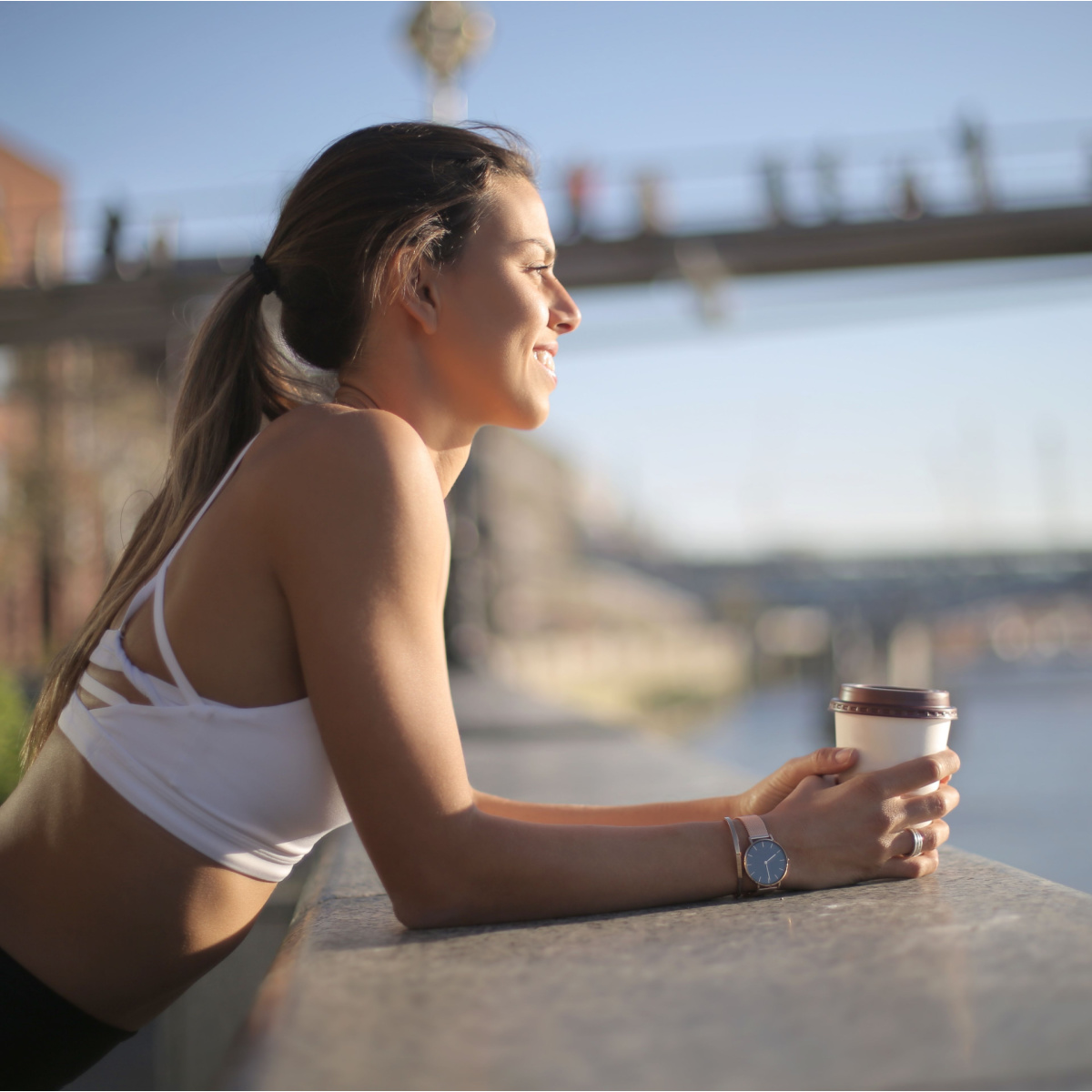 girl holding coffee cup in workout clothes outside