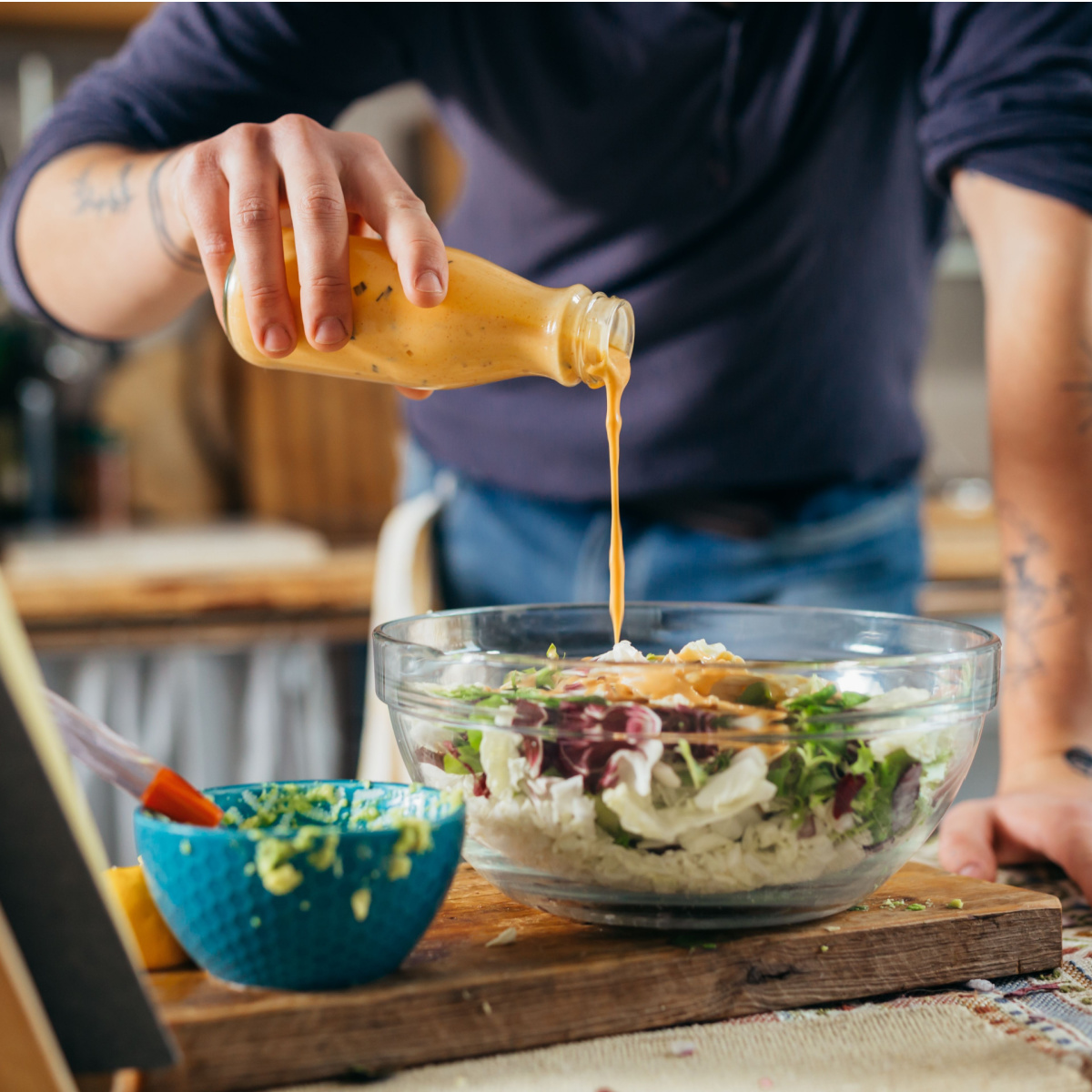 man pouring dressing over salad