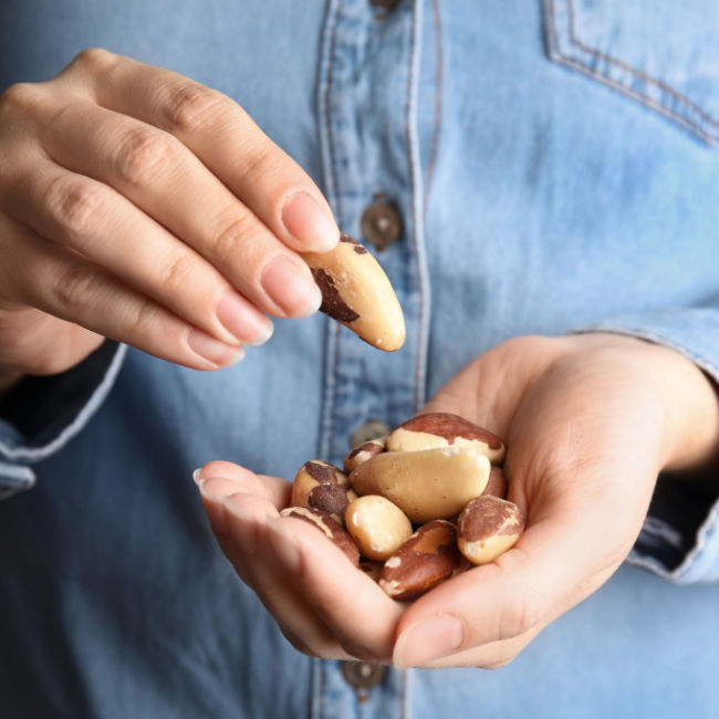 person holding handful of brazil nuts