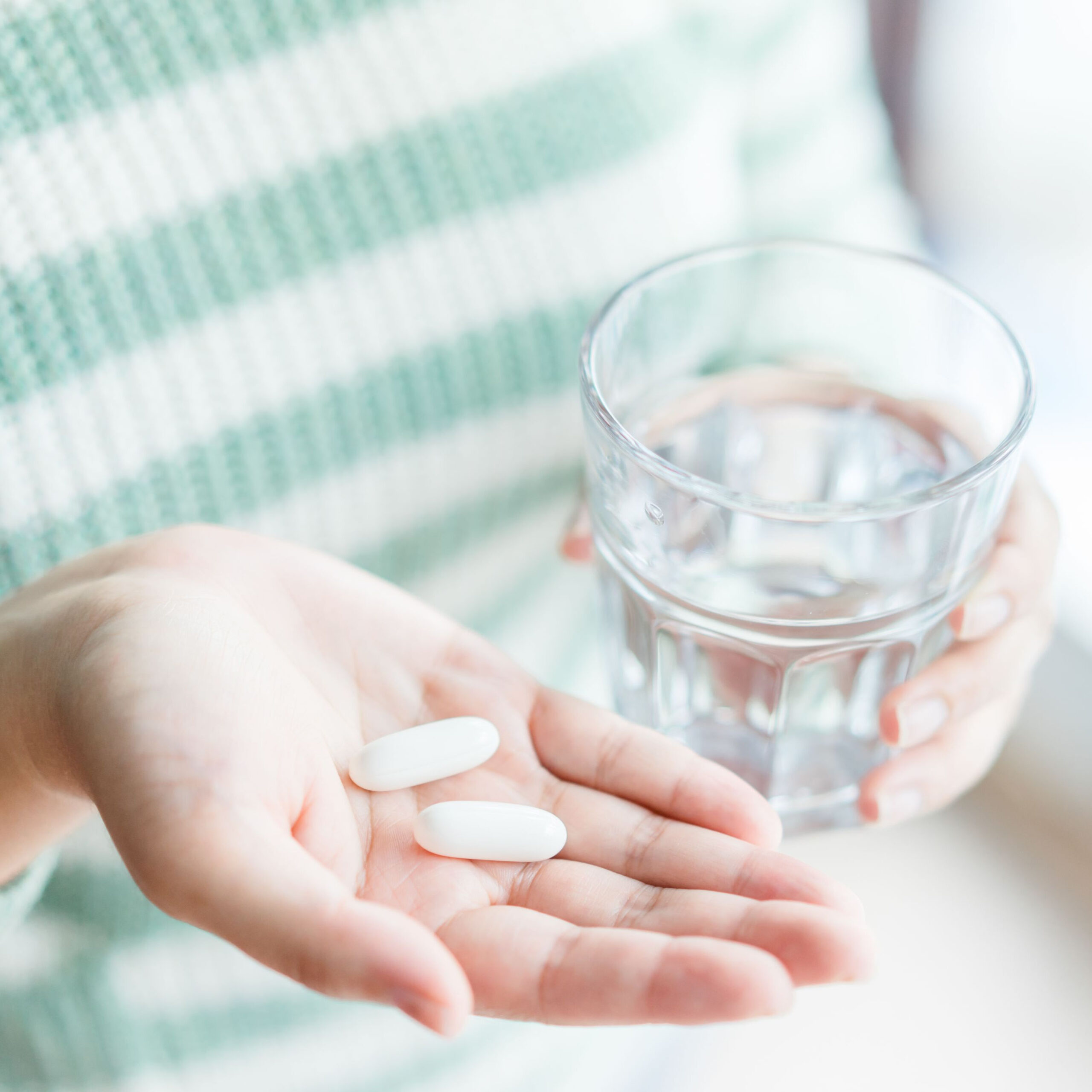 woman holding pills and glass of water