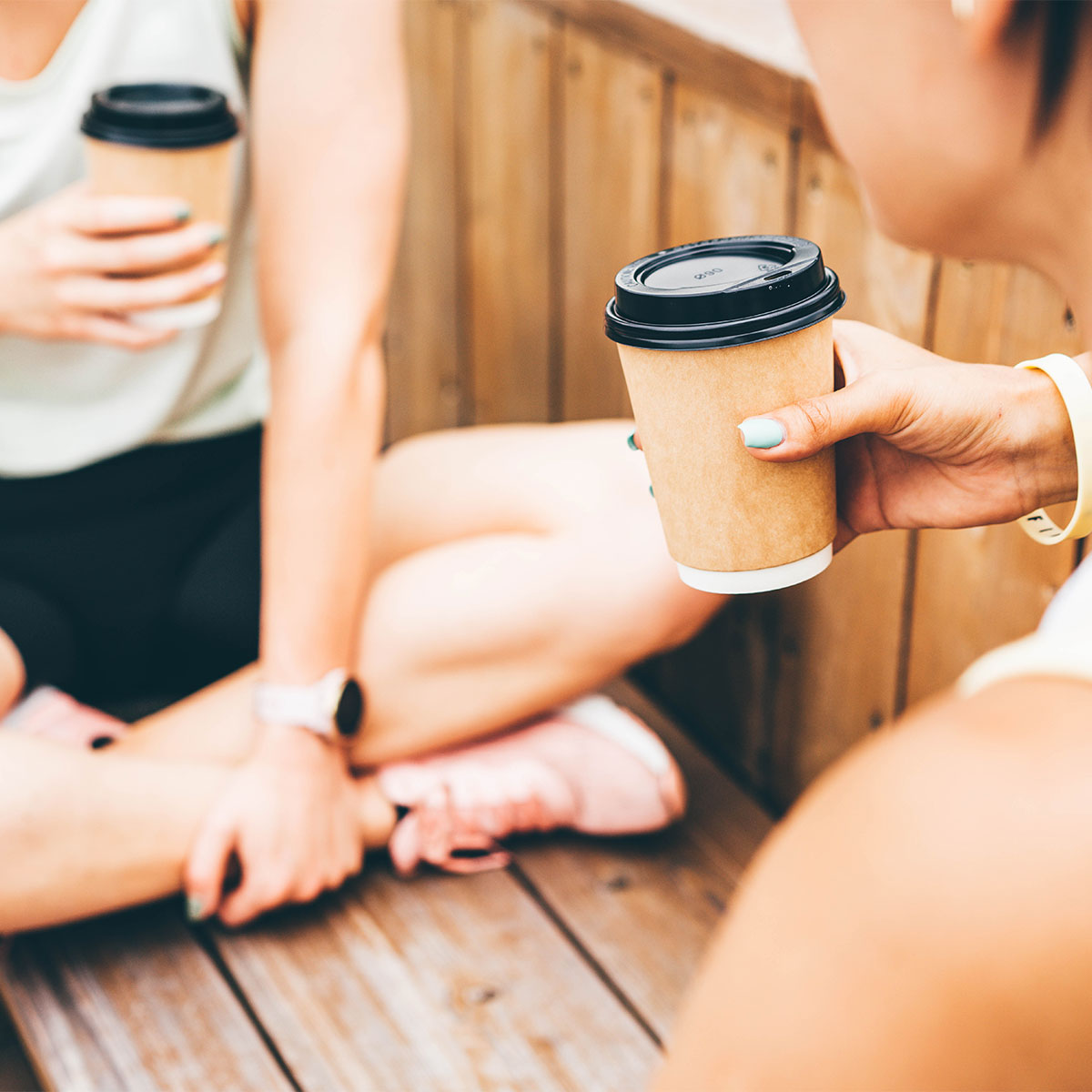 women drinking coffee from to-go cups after workout