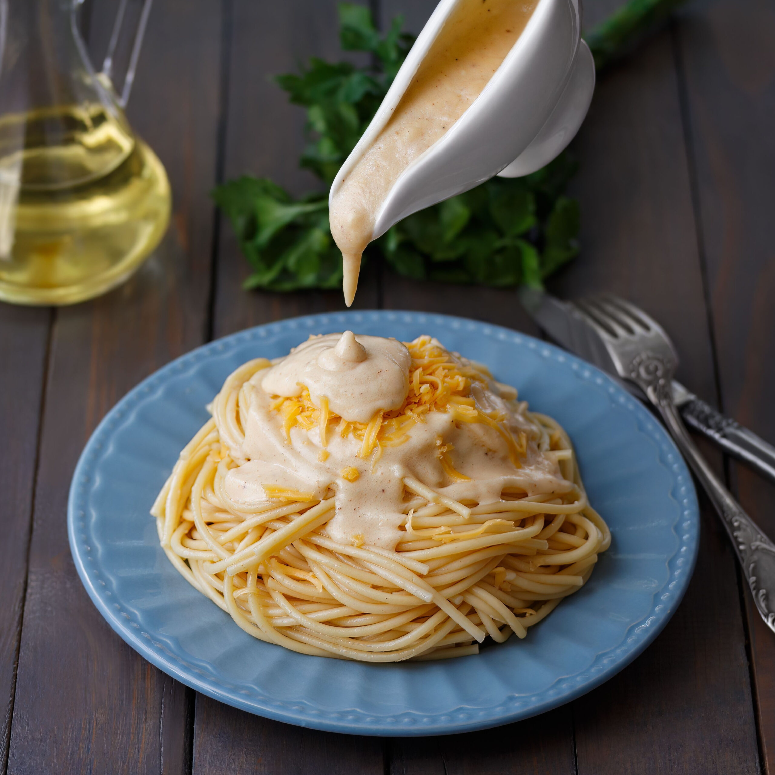alfredo sauce pouring onto pasta