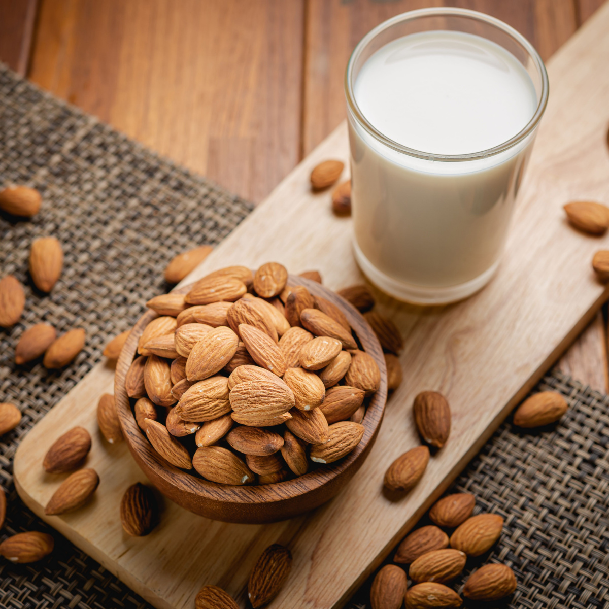 glass of almond milk beside bowl of almonds