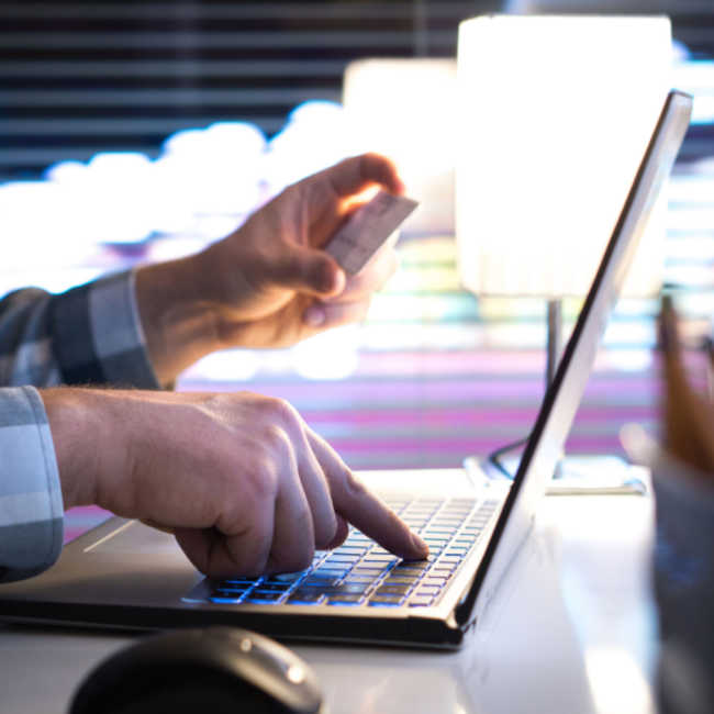 person holding credit card at computer