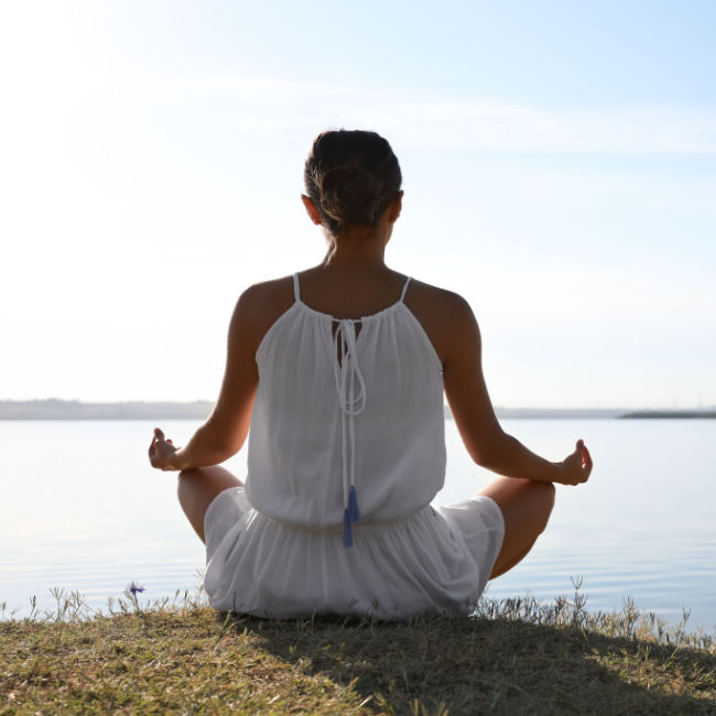 woman meditating by water