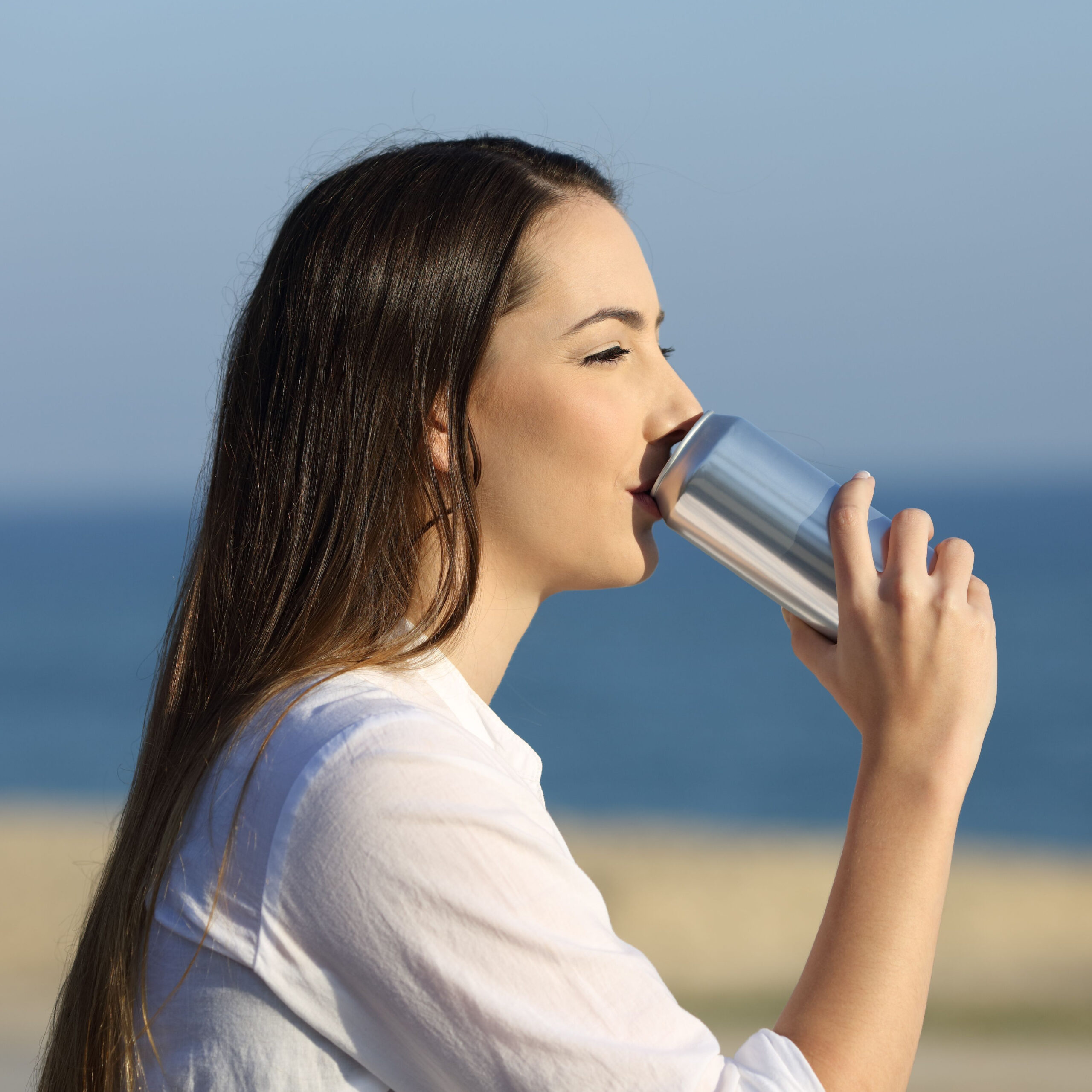 woman drinking from can on beach