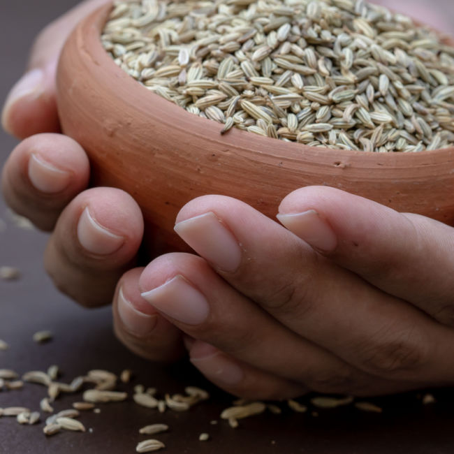 person holding bowl of fennell seeds