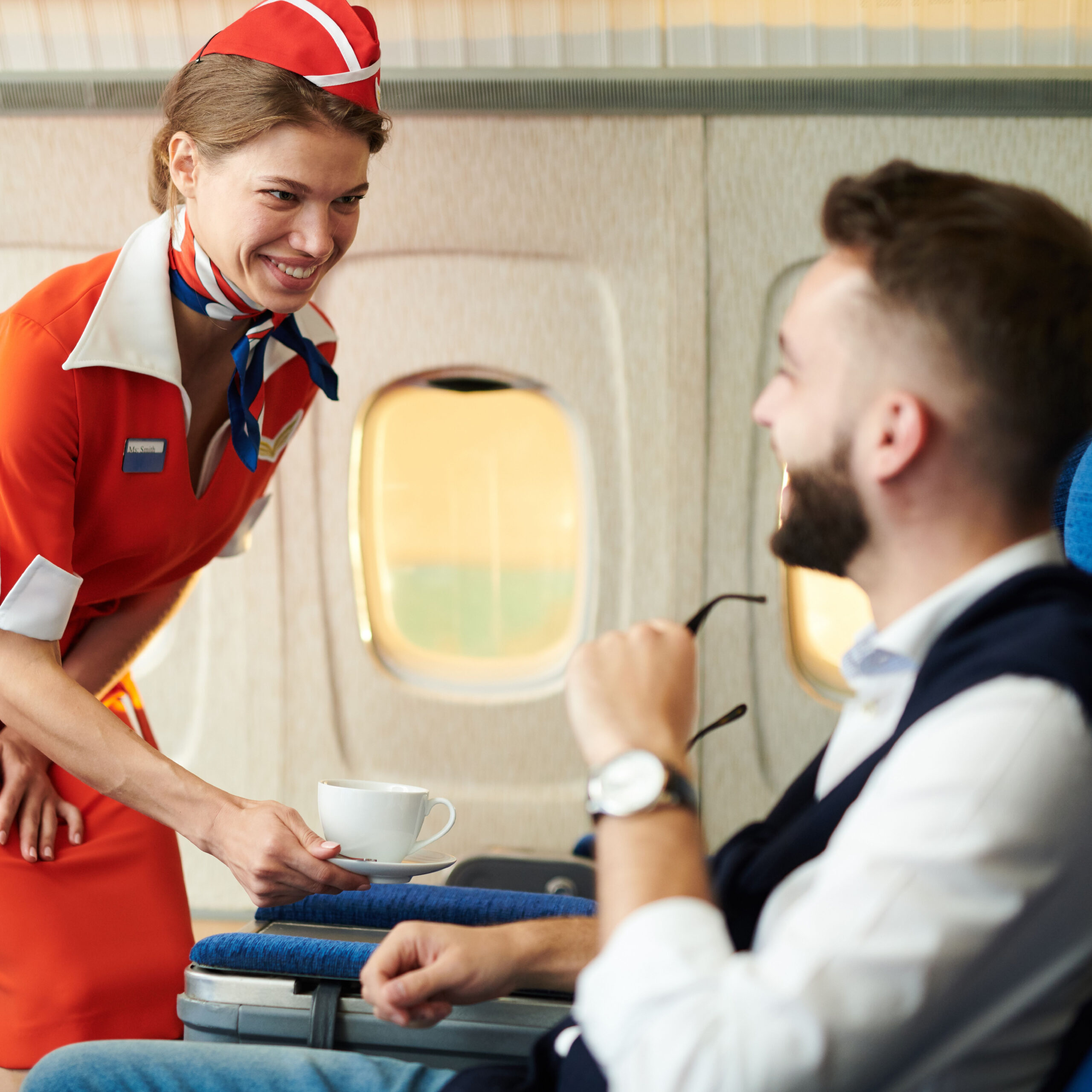 flight attendant giving man coffee on plane