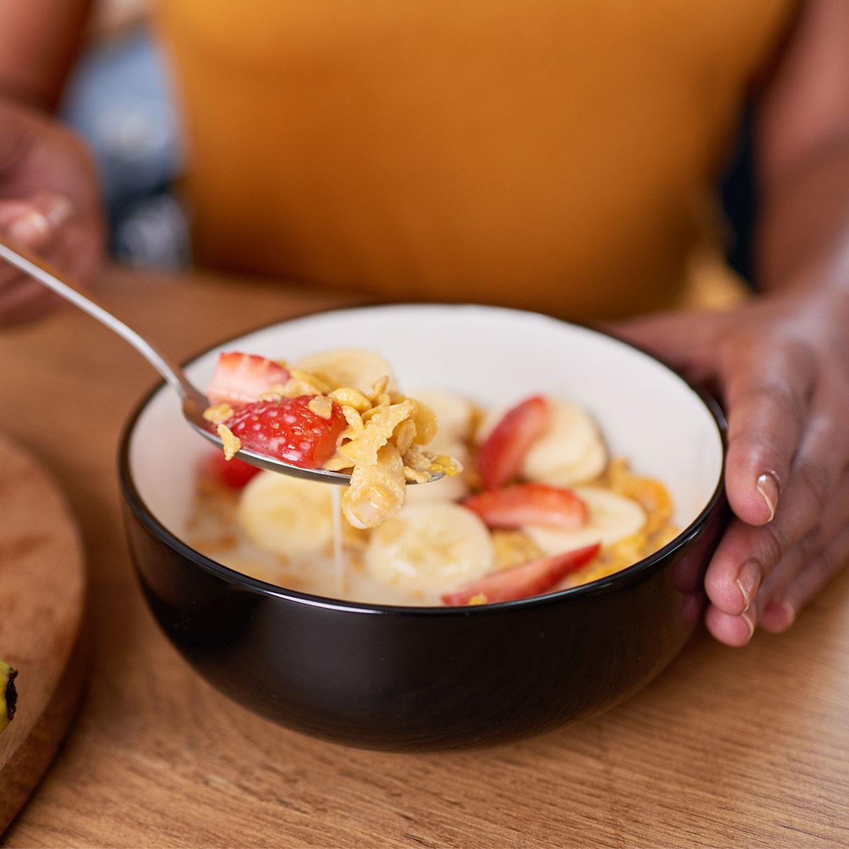 woman eating cereal with banana and strawberries