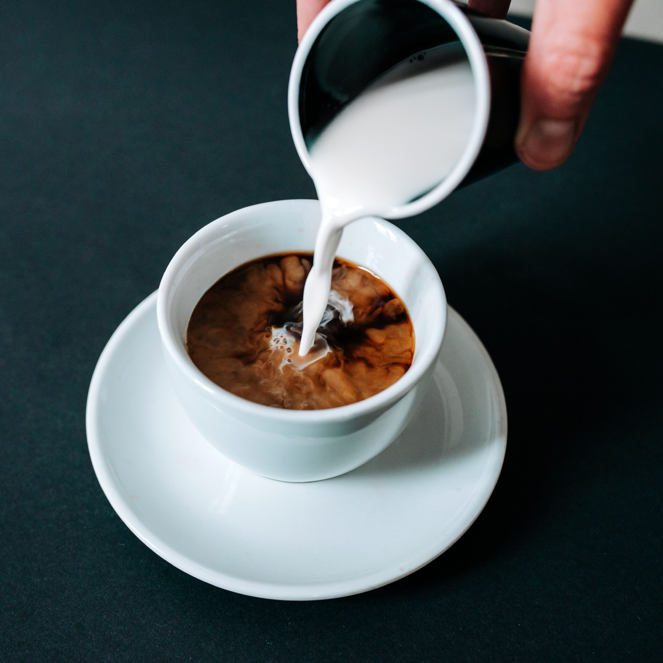 creamer being poured into cup of coffee