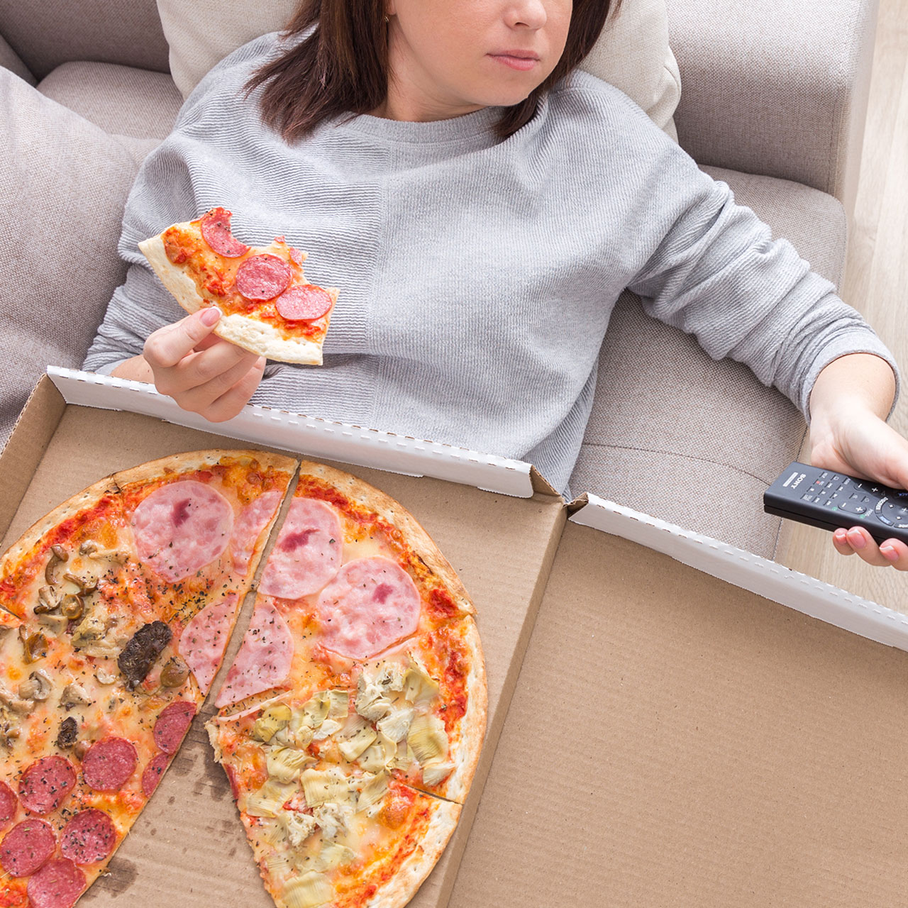 woman eating pizza and watching tv