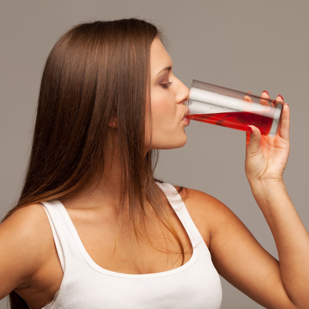 woman drinking a glass of red juice