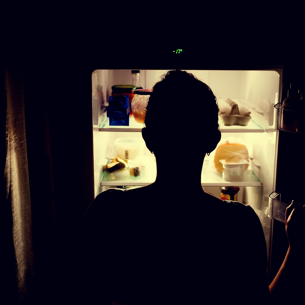 person looking into fridge late at night