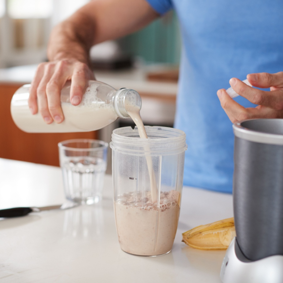 man pouring milk over protein powder