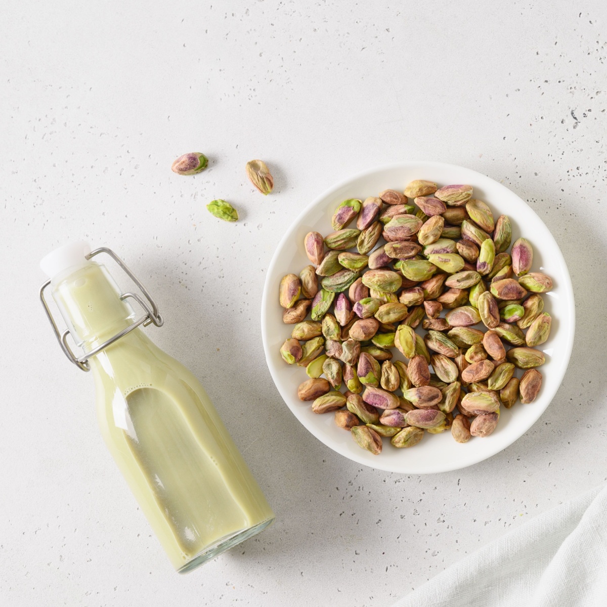 bottle of pistachio milk beside bowl of pistachios