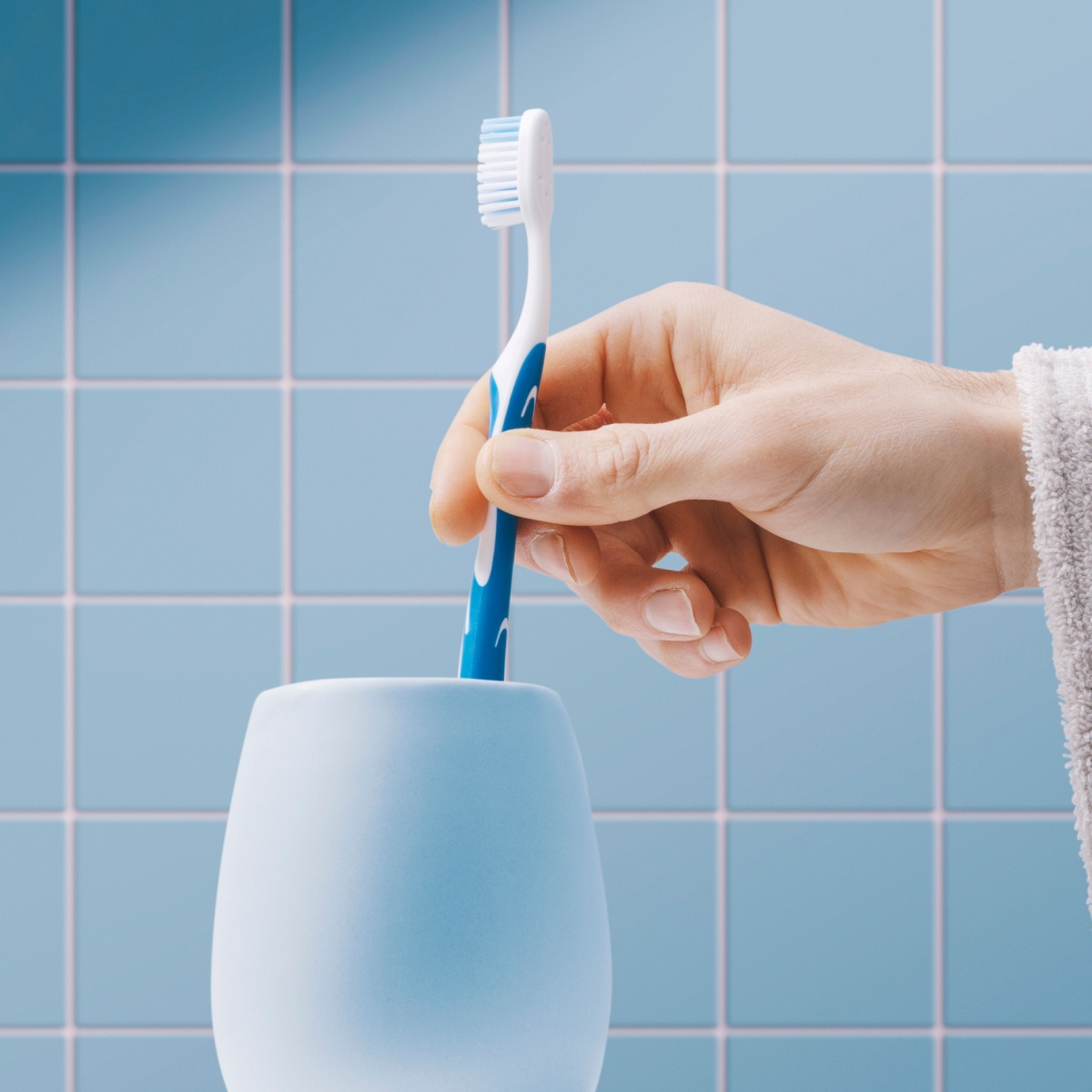 person taking toothbrush from toothbrush holder