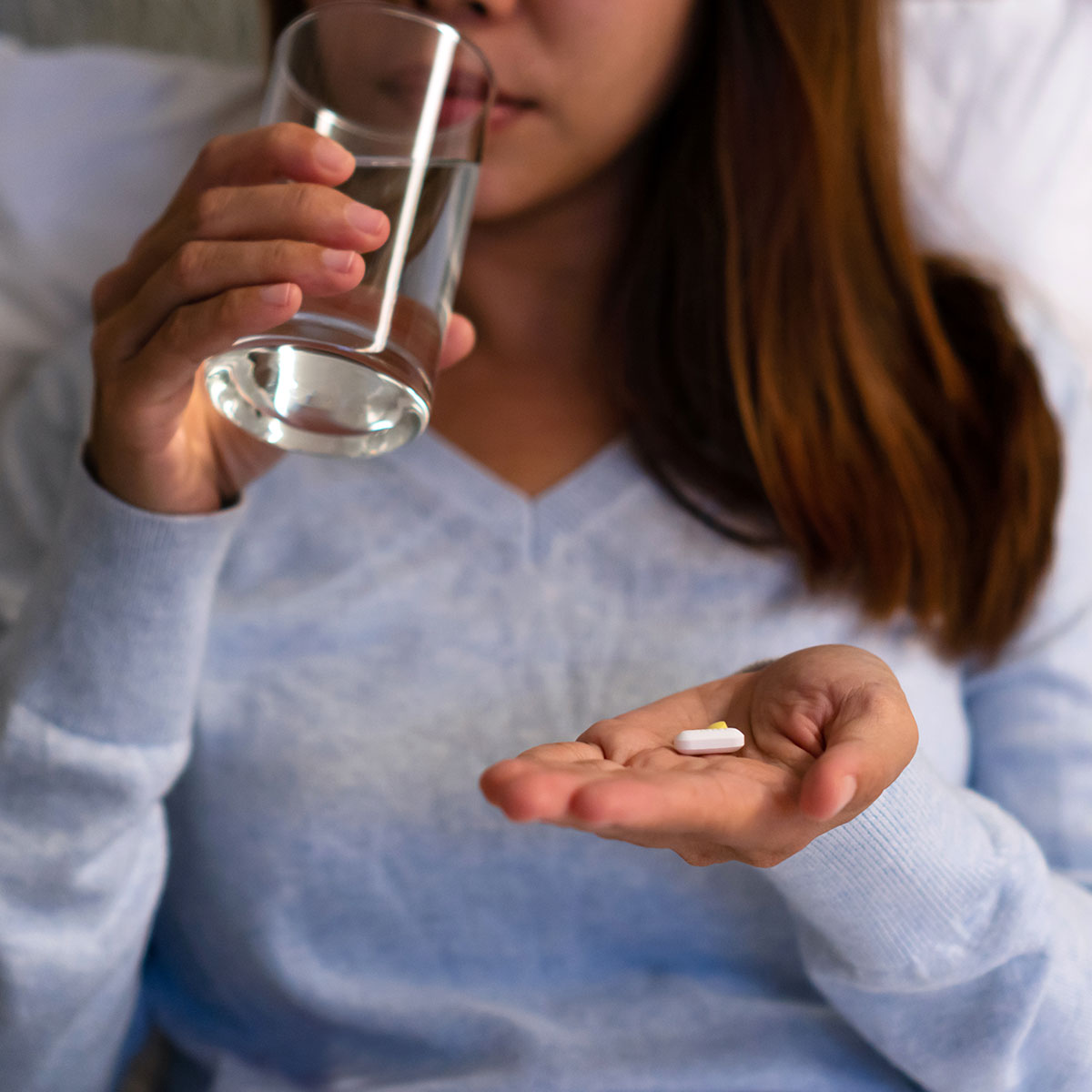 woman taking pill in bed