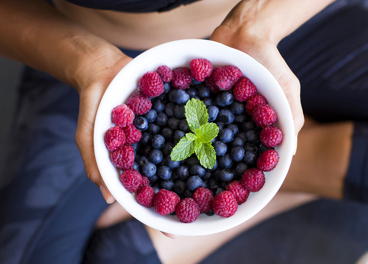 fit woman eating mixed berries