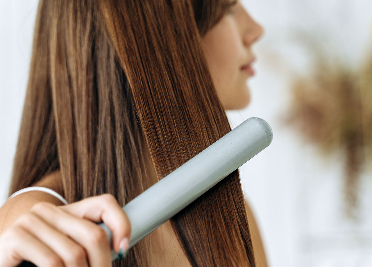 woman using a flat iron on her hair