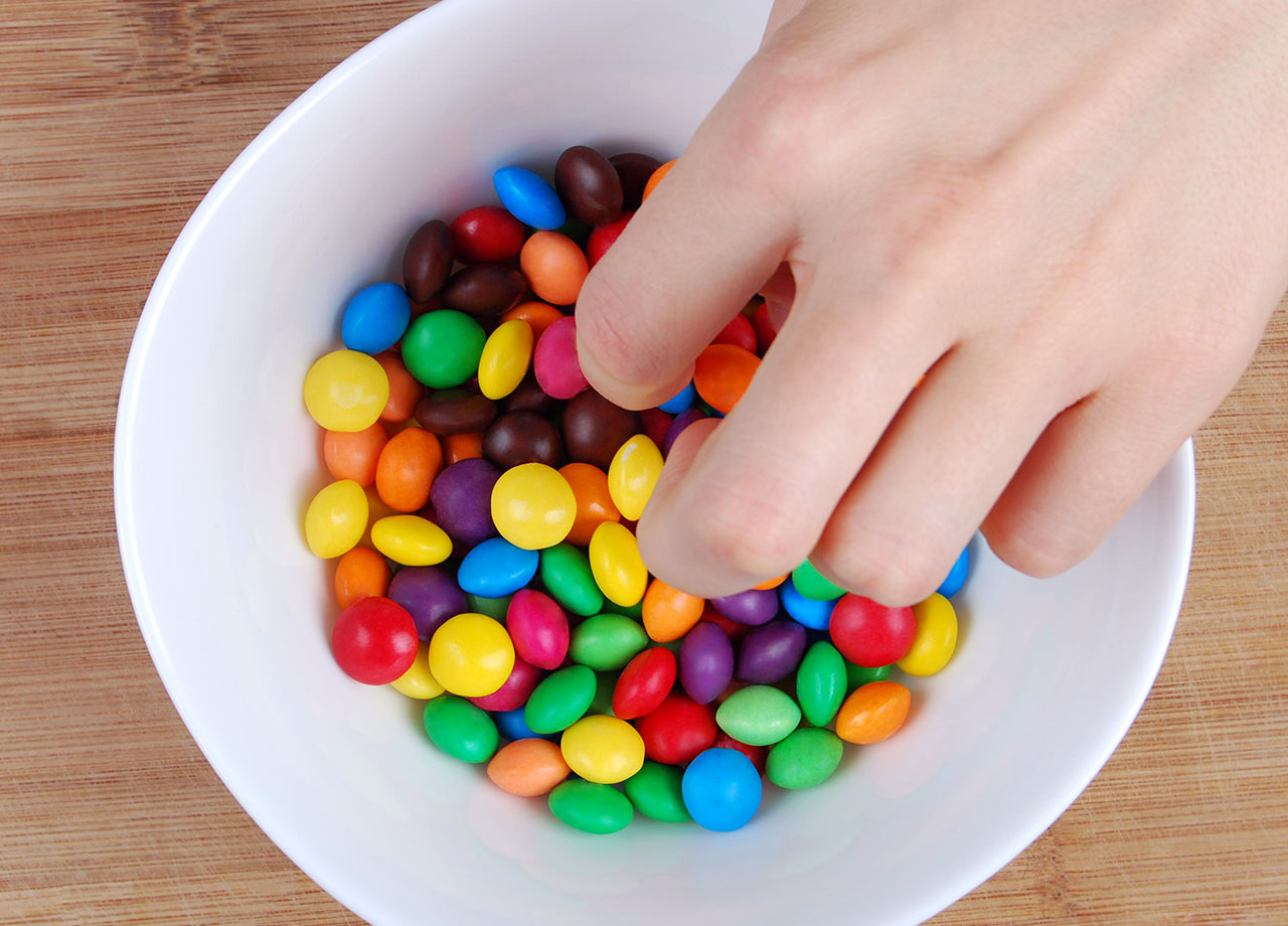 reaching into a bowl of mms