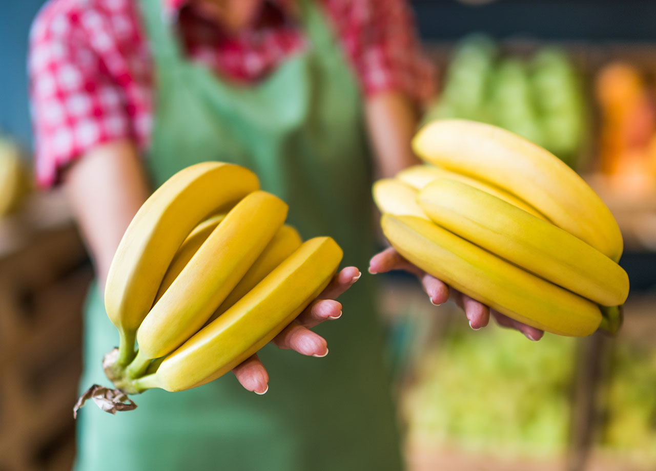 shopkeeper handing over yellow bananas