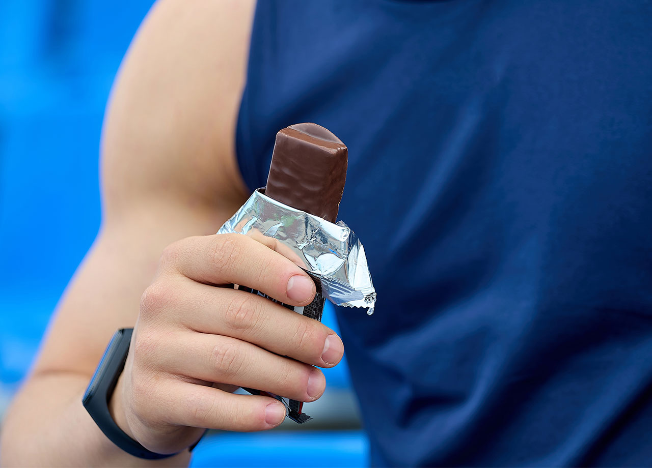 athletic man holding a chocolate protein bar