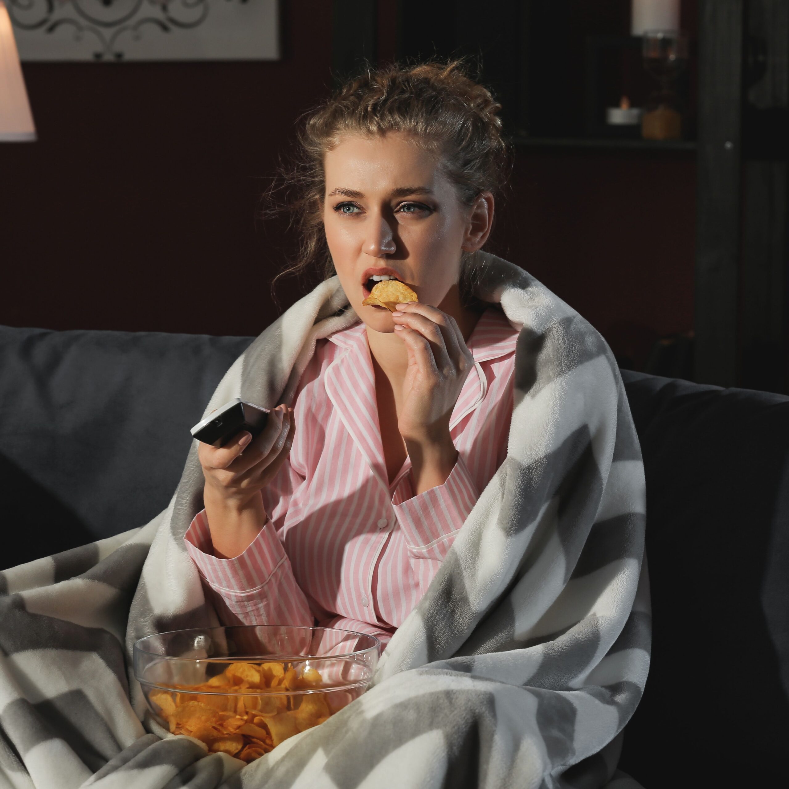 woman eating chips and watching tv on couch