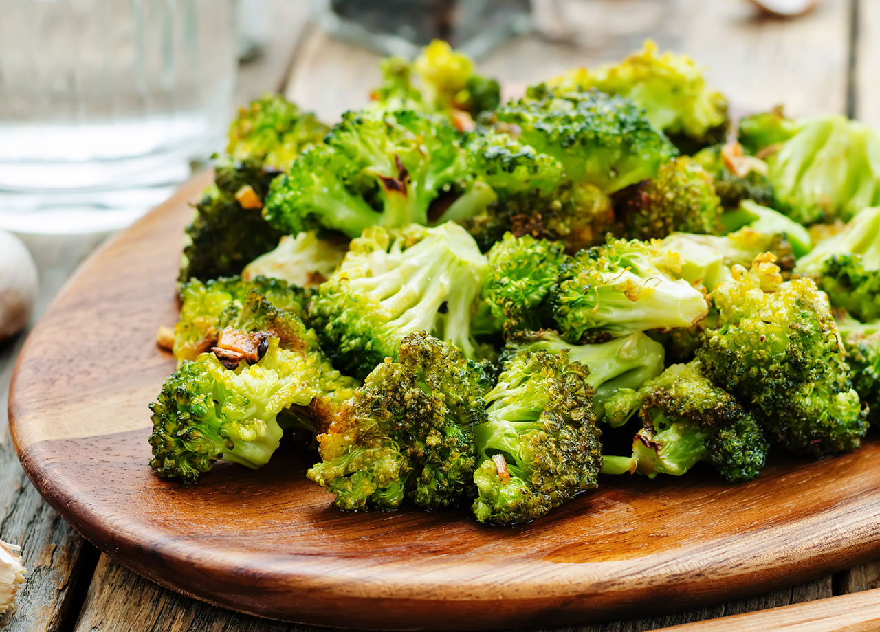 roasted broccolo with garlic on a dark wooden platter