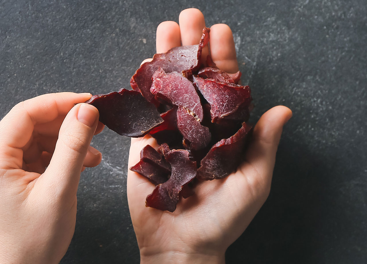 hands holding processed beef jerky