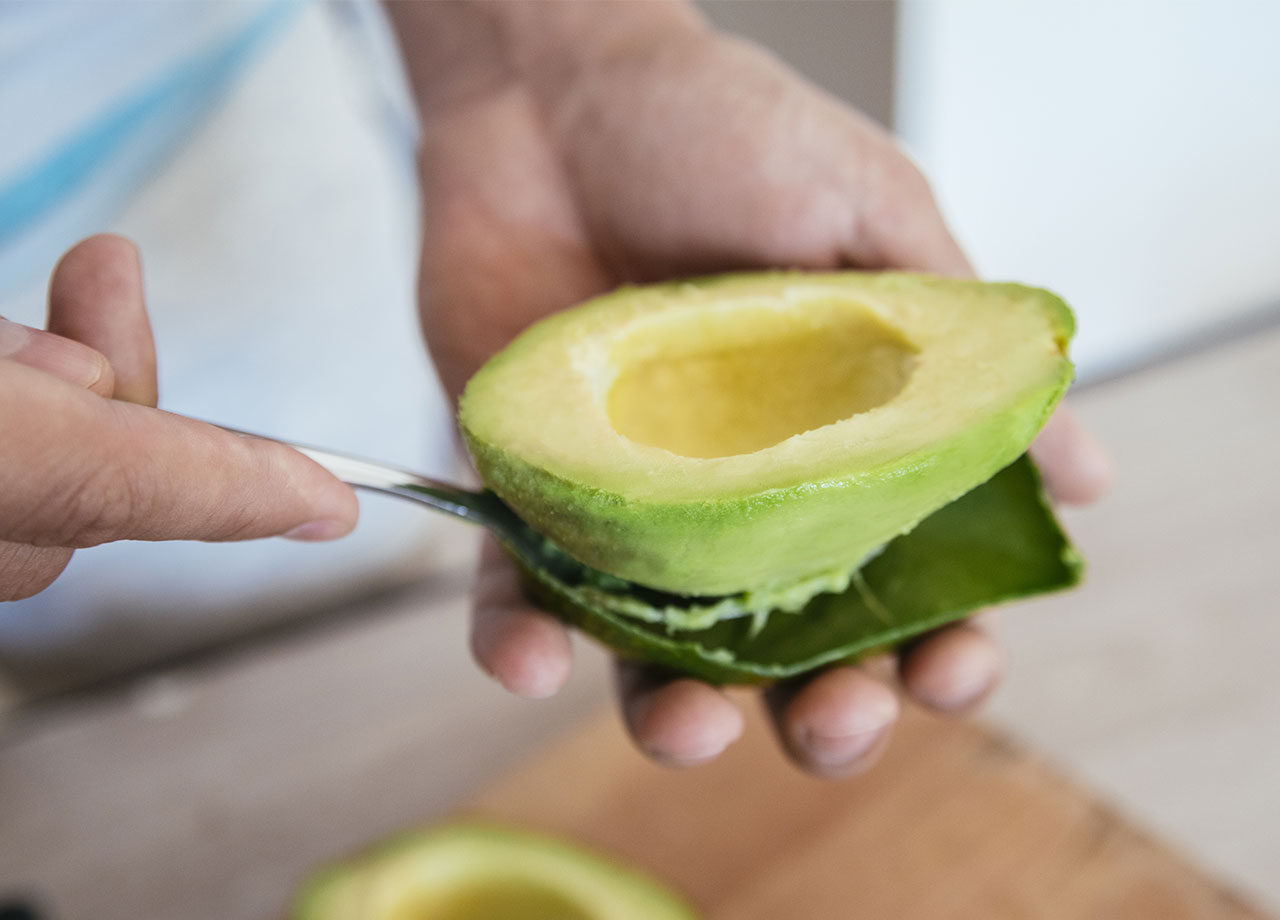 fresh avocado getting peeled with a spoon