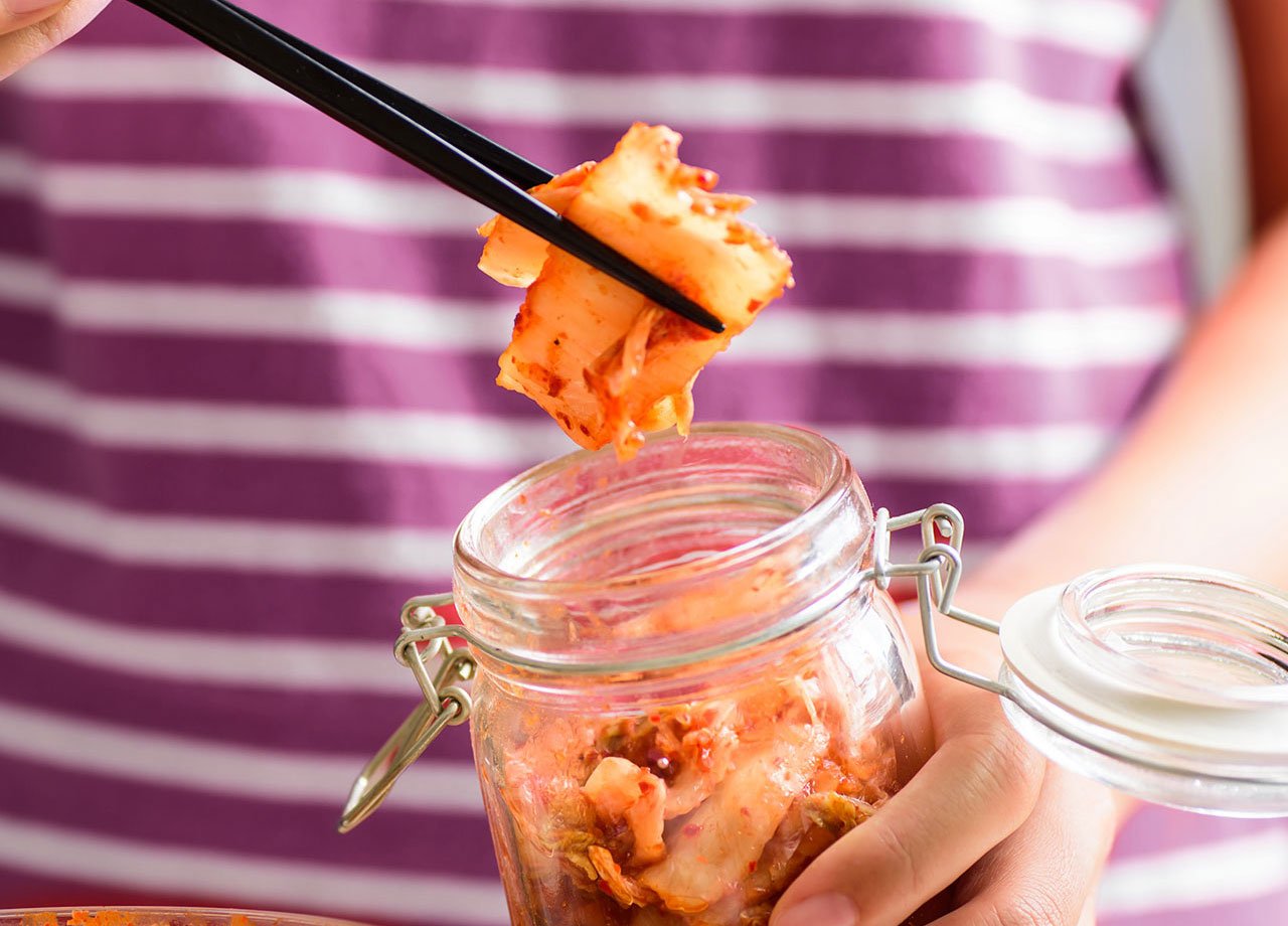 using chopsticks to pick kimchi from a jar