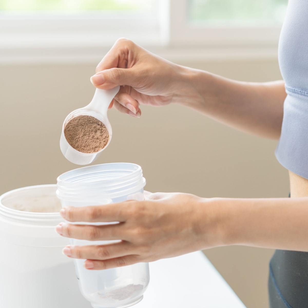 woman pouring creatine powder in cup