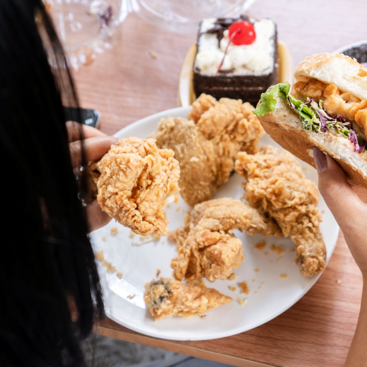 plate of fried chicken and burger in one hand