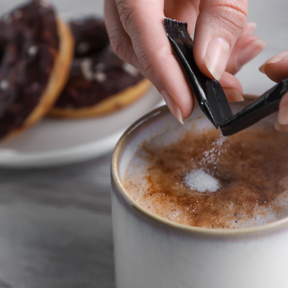 person adding sugar to coffee