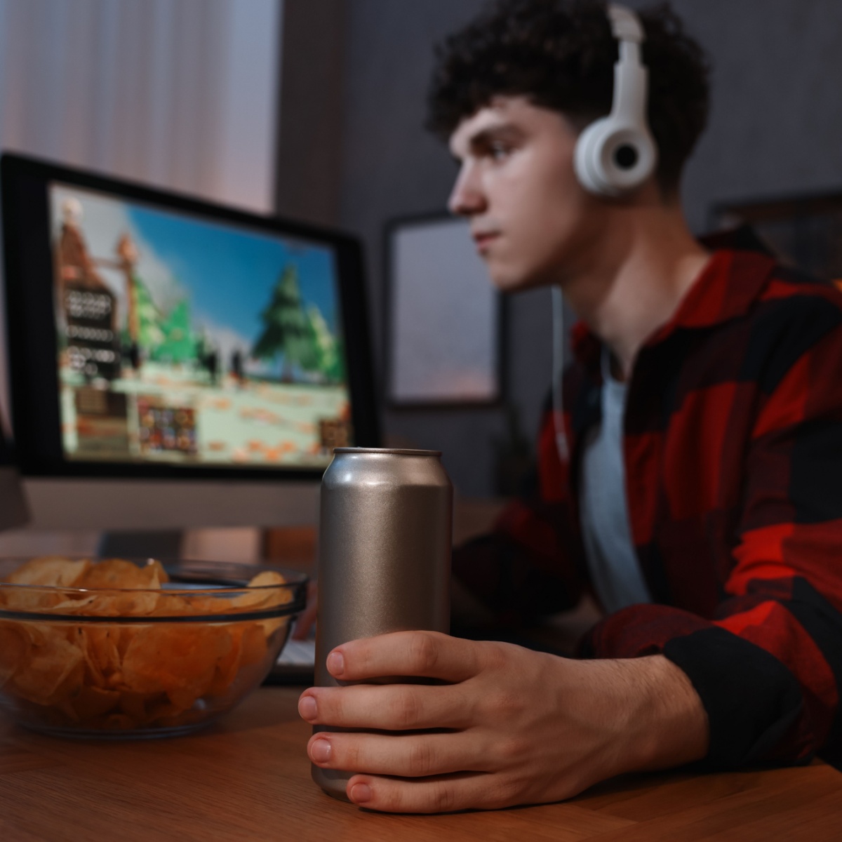 boy drinking energy drink while playing video games at night